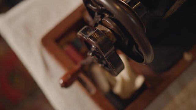 Overhead view antique sewing machine mechanism resting on patterned table, wooden base and metal handwheel, warm ambient light and quiet nostalgic atmosphere ready for restoration