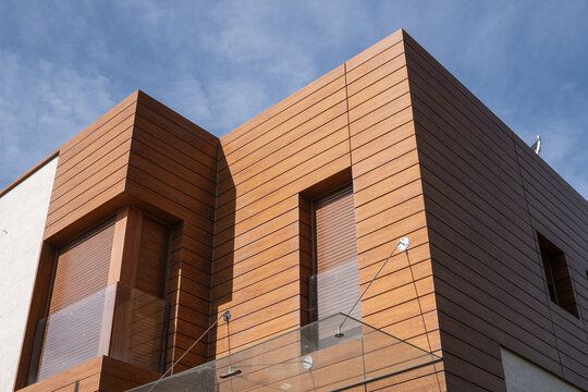 Modern residential building facade featuring wood cladding and glass balcony