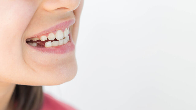 Healthy child smile with white milk teeth, visible gap from missing baby tooth, pink lips, smooth skin, closeup portrait fragment on light background with copy space, concept of pediatric dentistry