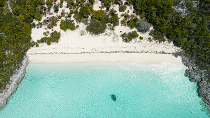 Aerial top down view of white sand beach and turquoise water, tropical island shoreline with green coastal vegetation in Exuma Bahamas. © K.roy