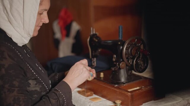 Elderly woman threading vintage sewing machine, hands steady over bobbin and needle, warm lamplit workshop, focused seamstress repairing garment with delicate stitches and heirloom fabric.