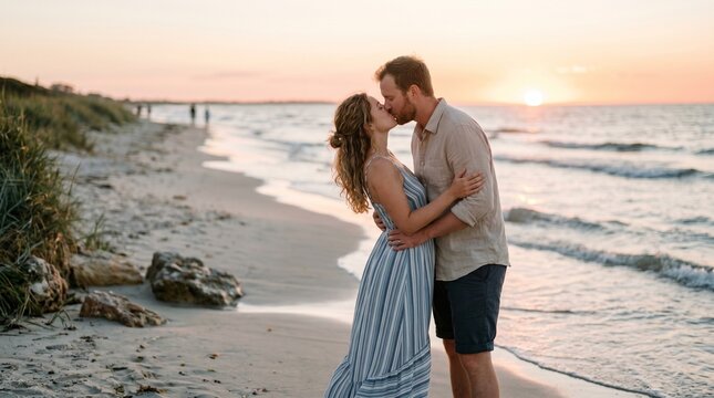 Romantic couple sharing a tender kiss while standing on the sandy beach during a beautiful golden sunset in this heartfelt candid photograph capturing their genuine love and deep emotional connection 