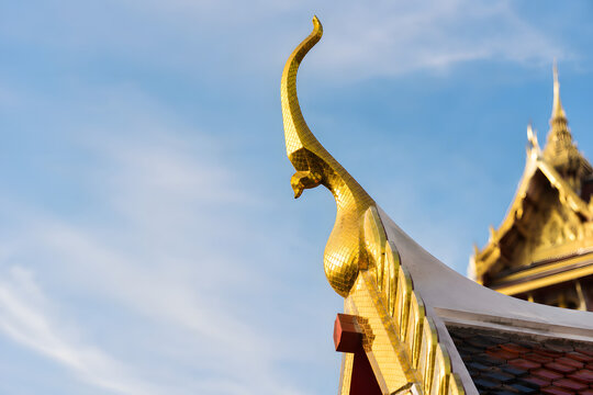 Golden Thai temple roof ornament chofa against blue sky