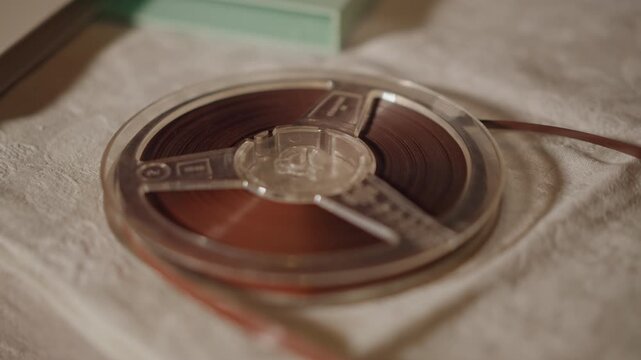 Reel tape spinning. Detailed closeup capturing spinning reel tape with warm cinematic tones. Highdefinition shot of reel tape rotating on linen with rich cinema style textures and warm hues