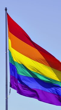 Slow motion gay pride flag blowing in the wind. Vertical Video.