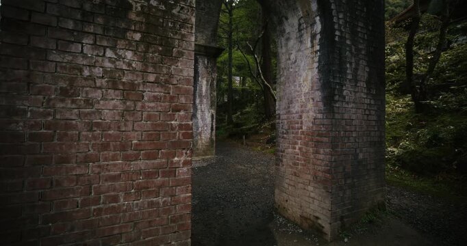 Steady cam movement towards tall brick bridge in Japanese forest area