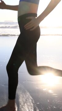 Athletic Asian woman jogging on the beach at sunset in Southern California. Slow motion. Vertical Video.