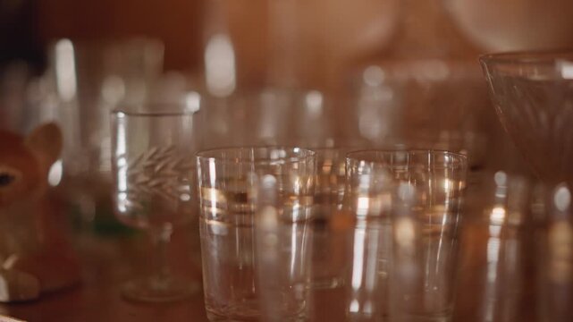 Soft intimate glass with ceramic fox peeking beside goblets and etched crystal, curator contemplative still life with warm amber highlights, delicate textures, muted depth of field and reflective