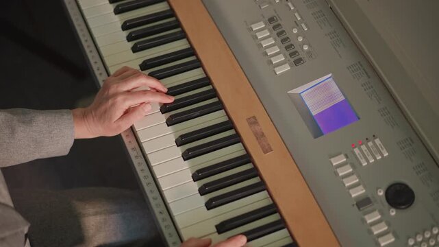 Vintage synthesizer display and operation. Producer manipulating synth controls during music production process. View from above showing keyboard buttons and user editing sound patch details
