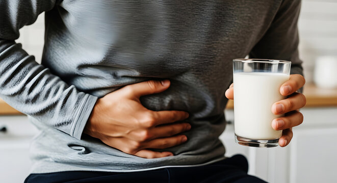 Person holding glass of milk with hand on stomach discomfort pain