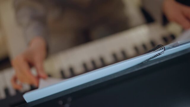 Hands adjusting music. Teacher preparing lesson sheets. Focused instructor arranging pages on keyboard scene. Detailed view of teacher modifying music sheets amid electronic keyboard background