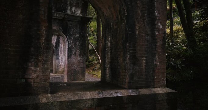 Slow steady cam movement looking through brick archways under bridge in Japan