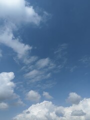 Obraz premium Blue sky background with fluffy white cumulus clouds. Natural background with copy space for background, template, summer concepts, and graphic design elements.