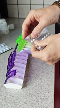 Diepenbeek. Person organizing daily medication into weekly pill organizer