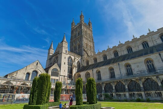 A grand medieval cathedral with a tall tower stands under a bright blue sky at Gloucester Cathedral - Gloucester - Gloucestershire - UK