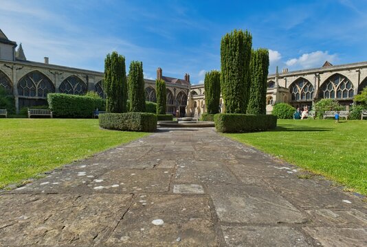 A tranquil garden courtyard features a stone path leading to a historic building at Gloucester Cathedral - Gloucester - Gloucestershire - UK