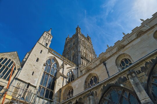 A low-angle shot of a majestic stone cathedral with a tall central tower against a bright blue sky at Gloucester Cathedral - Gloucester - Gloucestershire - UK