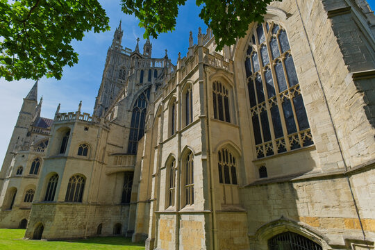 A sunny exterior view of a historic cathedral showcasing intricate Gothic architecture, including tall arched windows and a prominent tower at Gloucester Cathedral - Gloucester - Gloucestershire - UK
