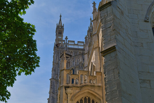 A majestic stone cathedral tower with intricate details stands against a bright blue sky at Gloucester Cathedral - Gloucester - Gloucestershire - UK
