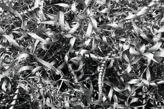 Metal shavings background from machining process. Industrial scrap texture. Curled steel swarf closeup. Manufacturing waste material. Metalworking industry detail.