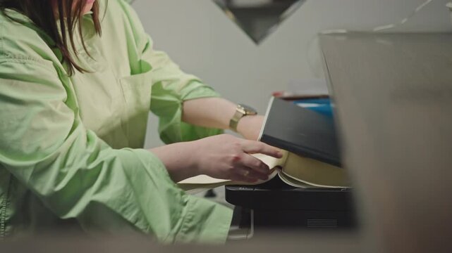Copying sheet music at office printer, white teacher loads pages into copier, adjusting settings, closeup of hands feeding paper, organized studio atmosphere, focused methodical pace
