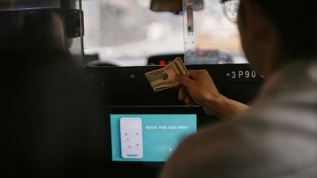 Backseat view of taxi driver using card reader and navigation screen