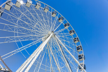 Obraz premium Ferris wheel viewed from below against clear blue sky with geometric structure and copy space