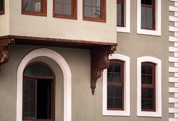 Traditional ottoman style house facade with wooden windows. Ottoman architecture facade featuring rustic wooden window frames, an elegant archway and decorative corbels on plaster walls. © ismailgazel