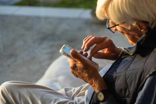 elderly man typing on smart phone outdoors at sunset