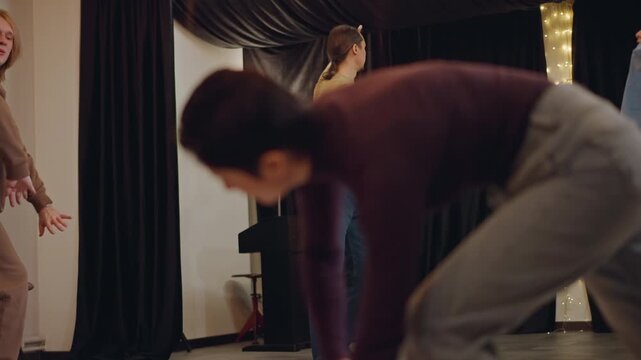 Male leader directing ensemble movement in studio, group practicing footwork and sync, casual clothing and intimate lighting, floorlevel closeups of feet and soles, energetic collaborative rehearsal
