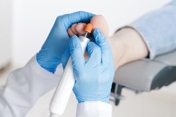 Fototapeta premium Podiatrist performing foot care procedure on patient toenails, pedicure and callus polish