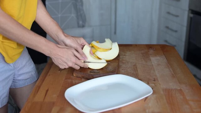 Person slicing fresh yellow melon on wooden cutting board in home kitchen preparation video Full HD