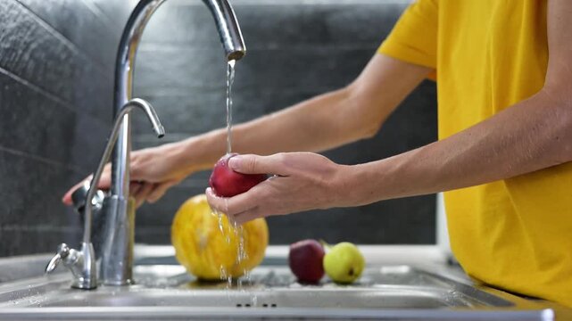 Washing ripe nectarine under running water in kitchen before eating video Full HD