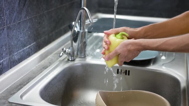Washing yellow sweet pepper under running water before cooking meal video Full HD