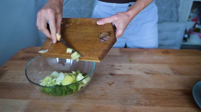 Woman adding chopped sweet pepper into fresh vegetable salad bowl in home kitchen video Full HD