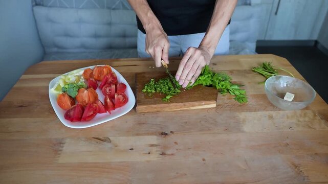 Woman slicing fresh herbs beside vegetables on kitchen Full HD video table