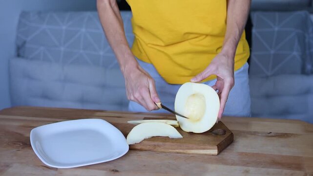Woman preparing yellow melon on cutting board in home Full HD video kitchen