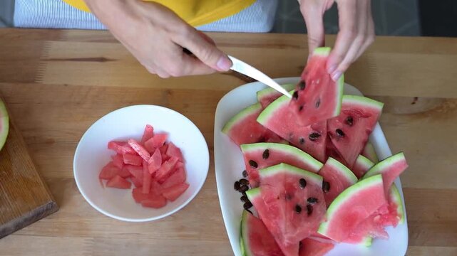 Woman removing knife after cutting watermelon into equal slices at home Full HD video