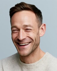 Fototapeta premium Portrait of handsome smiling man laughing naturally, clean studio lighting and soft background