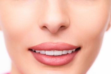Fototapeta premium Close-up of a woman's smiling lips with white teeth