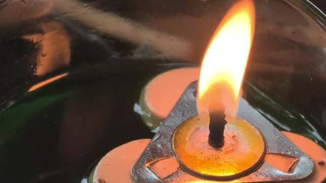 Elegant floating candle light burning peacefully in an oil lamp glass container, suitable for spa wellness, decoration, or spiritual concepts.