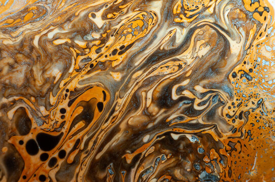 Abstract patterns in orange and brown paint on canvas during an art project