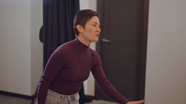 Female vocal coach in rehearsal room leading warmup exercises demonstrating breathing technique giving constructive feedback music teacher energy and focus casual outfit confident expression