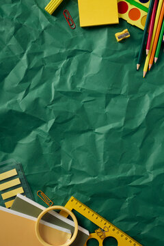 Vertical school supplies layout with top and bottom borders on green wrinkled paper.