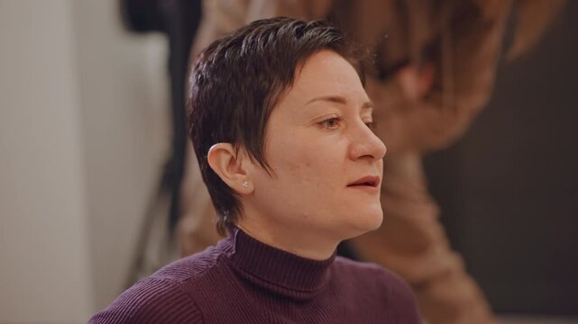 Female vocal coach in studio mentoring student through warmups and breathing exercises, closeup portrait of focused teacher with short hair wearing purple turtleneck, soft lighting with camera