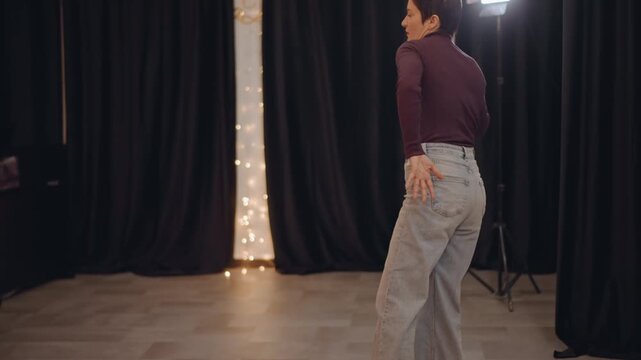 Dance rehearsal contemporary movement class floorwork focus two dancers practicing footwork and timing on studio floor black curtains string lights directional lamp instructor observing dynamic poses