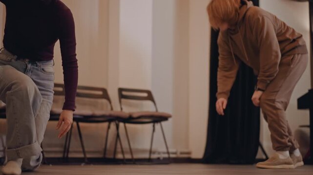 Intimate movement workshop exploring floorwork connection performers practicing contact improvisation and floor rolls chairs in background lamp light coach offering guidance hands reaching trust