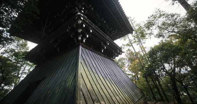 Smooth, low shot movement on tall, ancient Japanese structure in forest