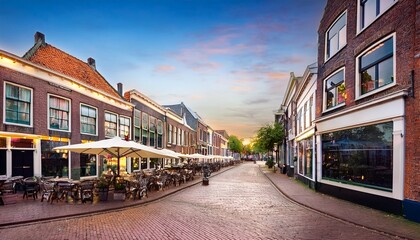 Naklejka premium small shopping street with restaurants in diepswal street at evening dokkum netherlands