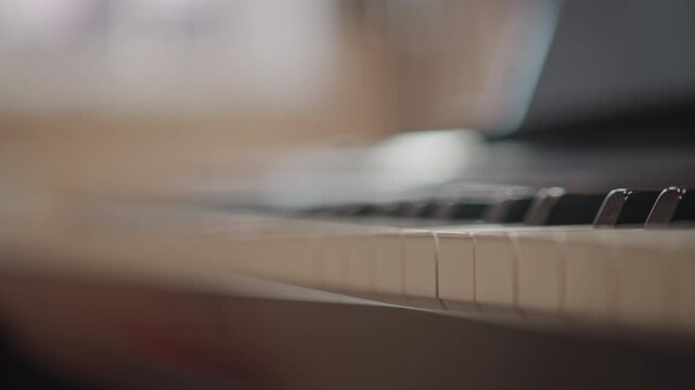 Blurred piano keys with laptop workspace, soft morning light, shallow depth of field, music producer workflow, mixing and arrangement mood, subtle coffee cup, focus on texture and rhythm, atmospheric